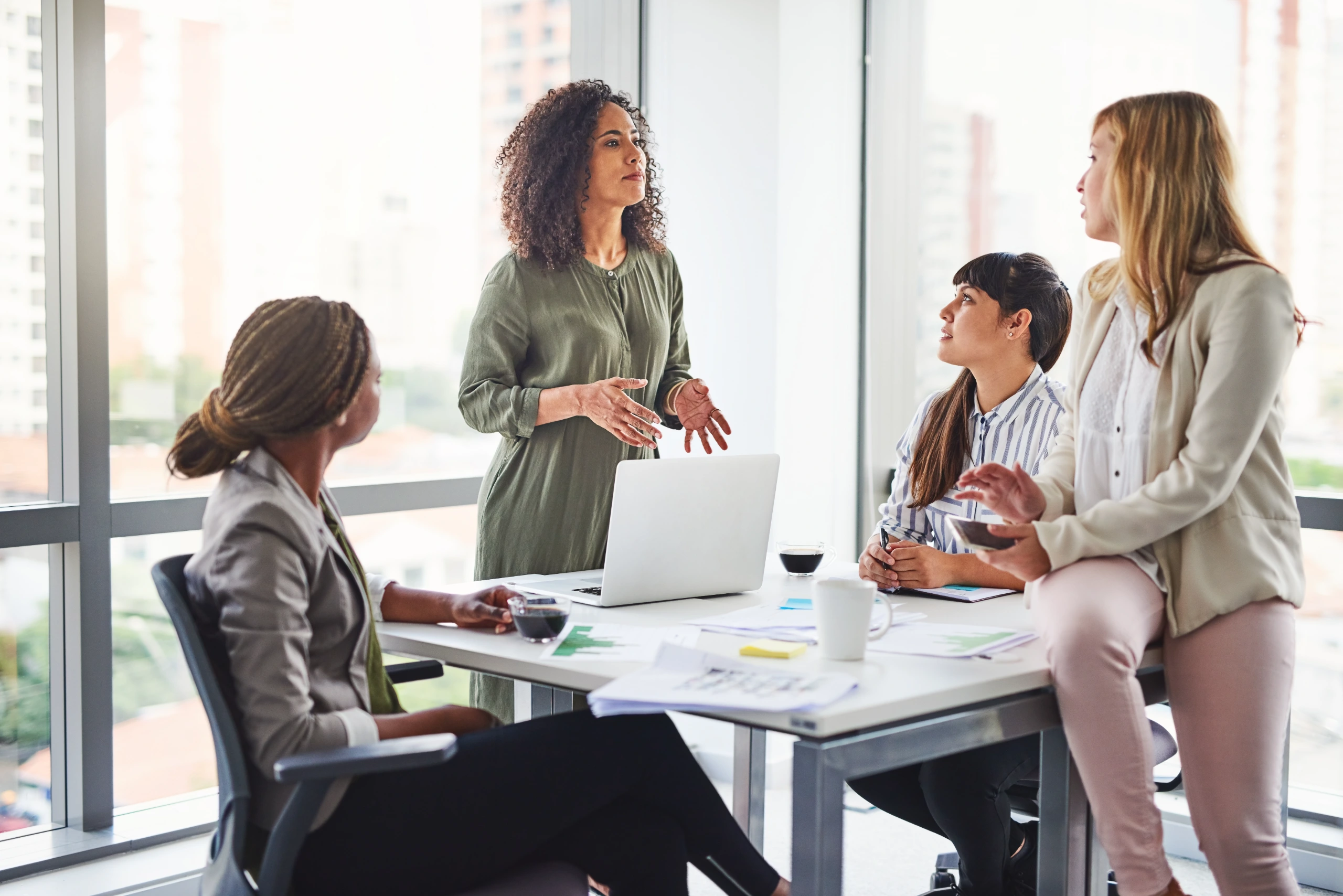 Businesswoman leading discussion with colleagues around meeting table.